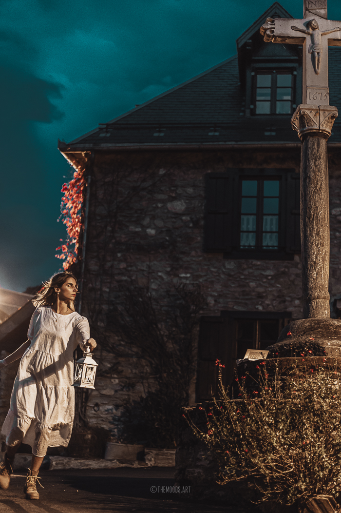 Photographie d'une femme dans un village au clair de lune le soir d'Halloween.
