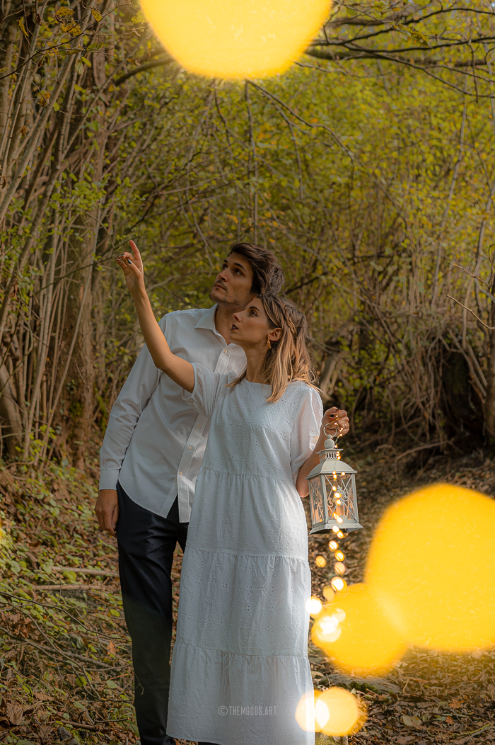 Photographie d'un couple avec un effet de bokeh dans la forêt.