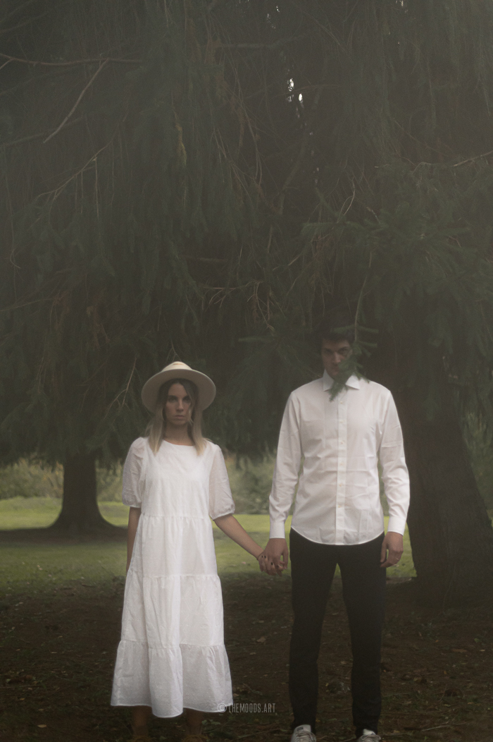 Photographie d'un couple creepy au milieu des sapins le soir d'Halloween.